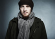 Artistic dark portrait of the young beautiful man in a cap and a