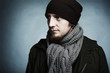 Artistic dark portrait of the young beautiful man in a cap and a