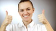 Woman gesturing a thumbs up sign, grey background