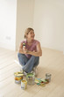 Smiling woman sitting with painting materials on floor