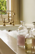 Bottles of Bath Oils on edge of bathtub filled with bubbles, water running from tap
