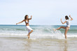 Two Young Women Splashing Each Other on Beach