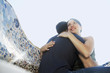 Young couple hugging on stone bench, portrait, low angle view