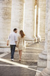 Couple walking between pillars, Rome, Italy, back view