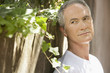 Middle-aged man standing by wall in shade