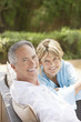 Contented middle-aged couple sitting outdoors on chairs, portrait