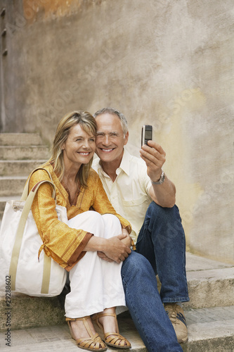Photo: Couple on steps photographing selves with phone camera Couple on steps photographing selves with phone camera