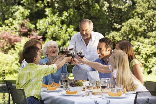 Photo: Family toasting at lunch table in back yard Family toasting at lunch table in back yard