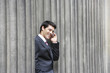 Businessman standing outside building between pillars on cell phone