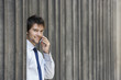 Businessman between pillars outside building talking on phone, portrait