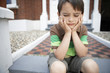 Sad little boy sitting on front steps of house, close up