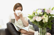 Foto: Woman sitting on sofa blowing nose Woman sitting on sofa blowing nose