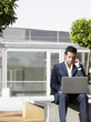 Foto: Businessman sitting alone in plaza using laptop and cell phone Businessman sitting alone in plaza using laptop and cell phone