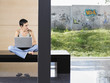 Photo: Young woman sitting down using laptop indoors Young woman sitting down using laptop indoors
