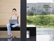 Photo: Young woman sitting down using laptop indoors, portrait Young woman sitting down using laptop indoors, portrait