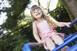 Girl Sitting on monkey bars in backyard, portrait