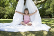 Young girl in backyard sitting in tent made of bed sheet