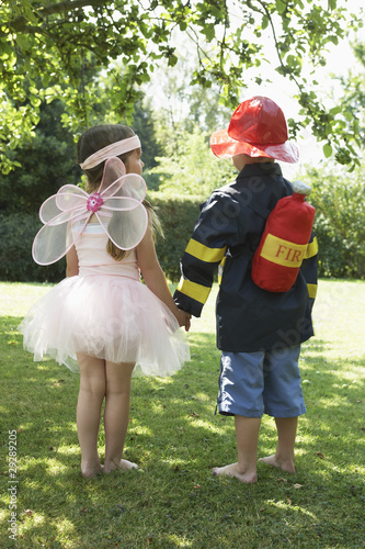 Photo: Girl and boy standing in park dressed up as fairy and fireman Girl and boy standing in park dressed up as fairy and fireman