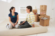Foto: Couple sitting on half-rolled carpet in new home Couple sitting on half-rolled carpet in new home