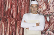 Foto: Butcher Standing, arms crossed, in front of raw meat in Meat Locker Butcher Standing, arms crossed, in front of raw meat in Meat Locker