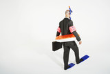 Photo: Middle-aged businessman in flippers, inflatable rubber ring, snorkel and goggles walking, carrying briefcase Middle-aged businessman in flippers, inflatable rubber ring, snorkel and goggles walking, carrying briefcase