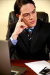 Young businessman sitting at desk and thinking