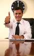  Businessman sitting at desk and  making a thumbs up gesture