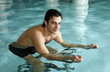 Young man on exercise bike in spa pool Young man on exercise bike in spa pool