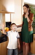 Woman talking on cell phone and boy doing bubble with gum in the kitchen