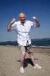 Male senior showing muscles on beach