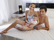 Couple laying on a bed with baby daughter