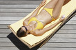 Woman in bikini on deck with mp3 player sunbathing