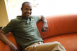 Man with earpiece and cellular phone sitting on sofa