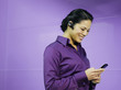 Businesswoman with mobile phone and earpiece in purple office