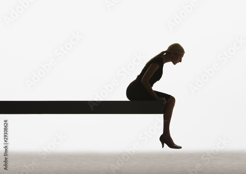 Photo: Woman sitting on a plank looking over ledge Woman sitting on a plank looking over ledge