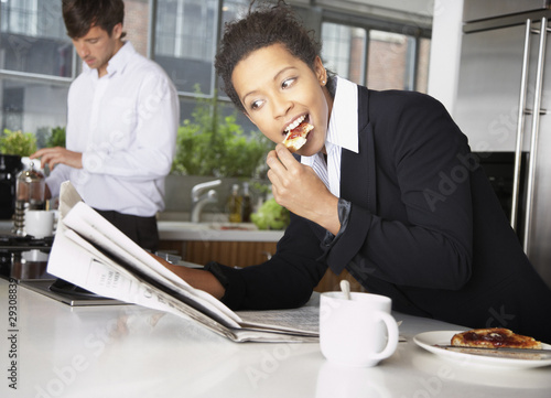 Photo: Woman eating toast with man in background Woman eating toast with man in background