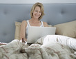 Woman sitting in bed using laptop