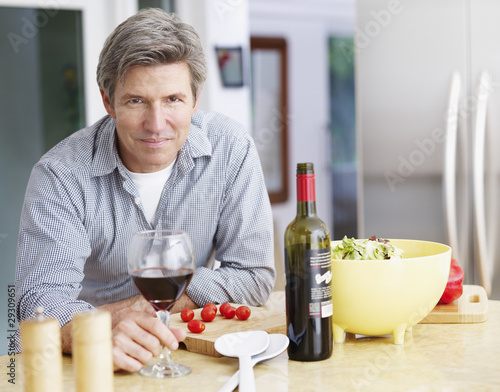 Photo: Man in kitchen preparing meal and drinking wine Man in kitchen preparing meal and drinking wine