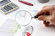 magnifying glass in hand and working paper