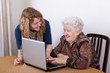 Images : Young girl teaching senior woman to work at computer