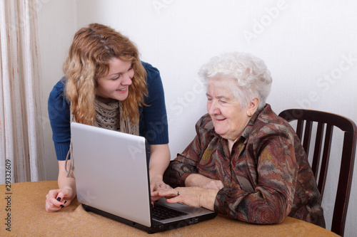 Photo: Young girl teaching senior woman to work at computer Young girl teaching senior woman to work at computer