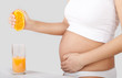 pregnant woman standing near table and making orange juice. pregnant woman standing near table and making orange juice.