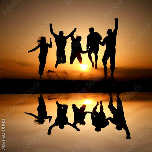 Photo: silhouette of friends jumping on beach in sunset silhouette of friends jumping on beach in sunset