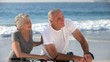 Aged couple with bikes looking at the beach