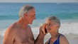 Elderly couple listening to a seashell