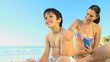 Beautiful mother putting sunscreen on her son