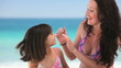 Beautiful mother putting sunscreen on her daughter