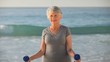Aged woman working his muscles with dumbbells