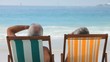 Elderly couple looking at the ocean sitting on beach chairs