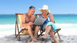 Video: Elderly couple using a laptop sitting on beach chairs Elderly couple using a laptop sitting on beach chairs